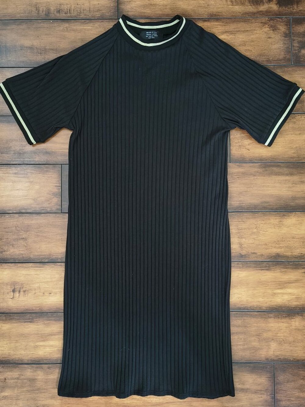 Black pleated dress with gold contrast trim around the neckline and sleeve cuffs